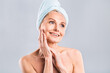 © denis_vermenko - Portrait of smiling senior woman feeling soft skin with hand after spa bath. Mature woman draped in towel looking at camera. Lady in bathrobe after shower isolated over white background.
