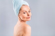 © denis_vermenko - Portrait of smiling senior woman feeling soft skin with hand after spa bath. Mature woman draped in towel looking at camera. Lady in bathrobe after shower isolated over white background.
