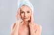 © denis_vermenko - Portrait of smiling senior woman feeling soft skin with hand after spa bath. Mature woman draped in towel looking at camera. Lady in bathrobe after shower isolated over white background.