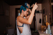 © Eloisa Ramos/Stocksy - Young androgyne woman combing hair with blow dryer at bathroom