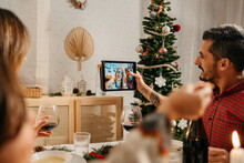 Family Doing A Videocall During Vegetarian Christmas Dinner In A Cozy Living Room