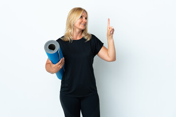 Wall Mural - Middle age woman going to yoga classes while holding a mat isolated on white background intending to realizes the solution while lifting a finger up