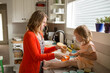 © Jennifer Bogle/Stocksy - Mom holds bowl while girl measures salt
