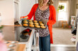 © Jennifer Bogle/Stocksy - woman holds hot tray of muffins