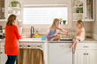 © Jennifer Bogle/Stocksy - Mother supervises daughters filling muffin tin