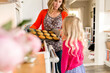 © Jennifer Bogle/Stocksy - Woman shows daughter muffins from oven