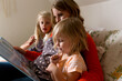 © Jennifer Bogle/Stocksy - Cute girl reads book with family