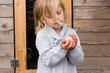 © Jennifer Bogle/Stocksy - Girl carefully cradles egg near chicken coop