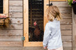 © Jennifer Bogle/Stocksy - Girl looks at chicken in homemade coop