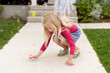 © Jennifer Bogle/Stocksy - Girl crouches on sidewalk with chalk