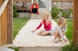 © Jennifer Bogle/Stocksy - Sisters draw with sidewalk chalk