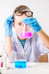 Wall Mural - a schoolboy studies multi-colored substances in test tubes, conducts experiments - a portrait on a w