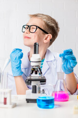 Wall Mural - a schoolboy with a microscope examines chemicals in test tubes, conducts experiments - a portrait on