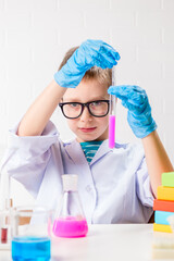 Wall Mural - a schoolboy studies multi-colored substances in test tubes, conducts experiments - a portrait on a w