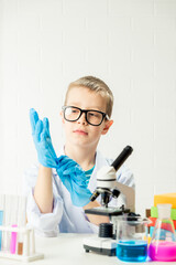 Wall Mural - a schoolboy with a microscope examines chemicals in test tubes, conducts experiments - a portrait on