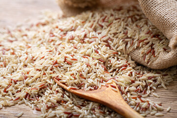 Canvas Print - Raw brown rice on a wooden table