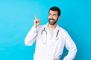 Wall Mural - Young caucasian man over isolated background wearing a doctor gown and pointing up