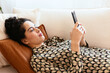 © BONNINSTUDIO/Stocksy - Young woman using smartphone on sofa