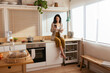 © BONNINSTUDIO/Stocksy - Woman sitting on counter and browsing smartphone in morning
