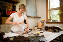 Artist uses mallet in leather studio