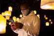 © VICTOR TORRES/Stocksy - Man in dark room with glowing lanterns using a cellphone