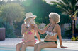 © Ivan Gener/Stocksy - Mature friends in bikinis toasting by a pool