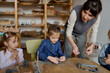 © Tatiana Timofeeva/Stocksy - preschool teacher with children in ceramics lesson at  art school