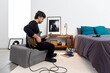© Bisual Studio/Stocksy - Focused man with laptop playing guitar in bedroom