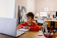 Young Boy Concentred Looking At A Computer Screen During Remote Classes At Home