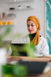 © Studio Marmellata/Stocksy - Smiling woman browsing tablet during work in modern workplace