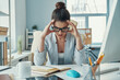 © gstockstudio - Stressed young woman in smart casual wear keeping head in hands while sitting in the office