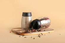 Jars With Black Pepper Powder And Peppercorns On Color Background