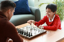 Father And Son Playing Chess At Home