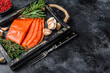 Smoked sliced salmon fillet in a wooden tray with herbs. Black background. Top view. Copy space
