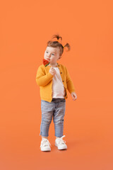 Poster - Cute little girl eating lollipop on color background