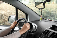 Young Woman Holding Hands On Steering Wheel And Air Freshener Hanging In Car