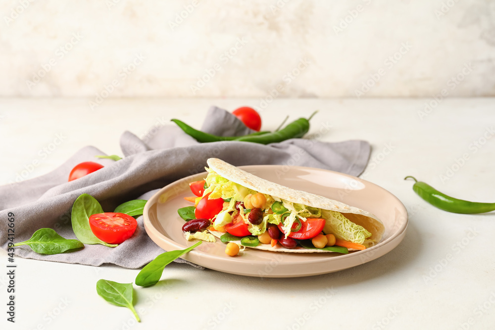 Plate with tasty vegetarian taco on light background