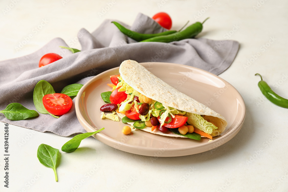 Plate with tasty vegetarian taco on light background
