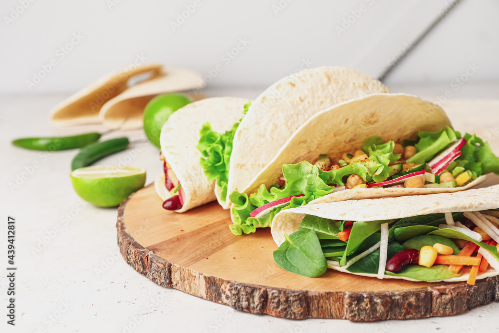 Board with tasty vegetarian tacos on light background, closeup