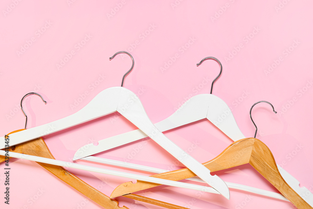 Stylish clothes hangers on color background