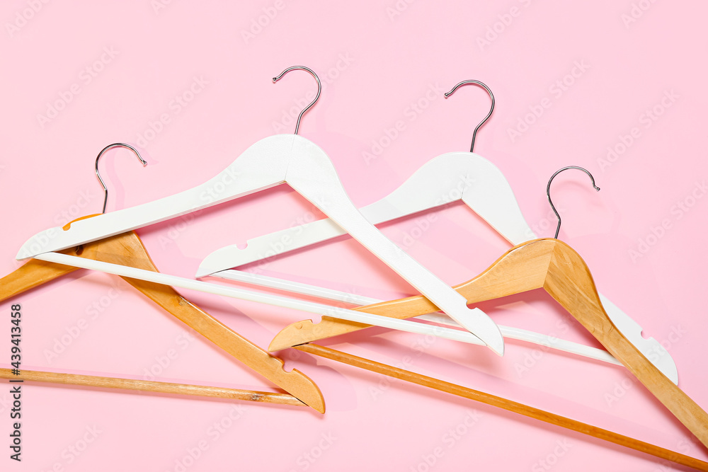 Stylish clothes hangers on color background