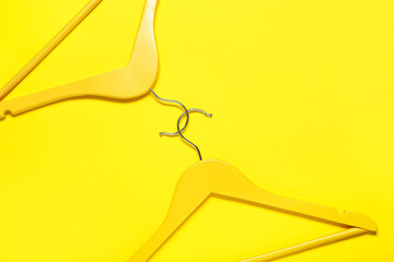 Stylish clothes hangers on color background