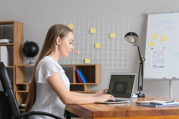 Canvas Print - Young woman with laptop checking her e-mail in office