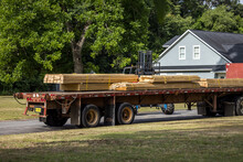 A Flatbed Truck Carrying A Load Of Construction Lumber Wood For The Building Of A New House
