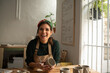 © Malquerida Studio/Stocksy - Smiling ceramist young woman Making Clay cups  in her studio