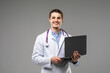© F8  \ Suport Ukraine - Concentrated male doctor using laptop over grey background.