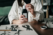 Young Woman Writing Japanese Kanji Characters With A Brush And Ink