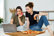 Young Female Friends With Pizza Enjoying Online Shopping At Home
