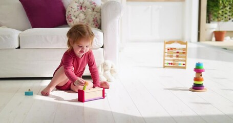 Wall Mural - cheerful toddler baby girl playing wooden toys at home, sunny summer day