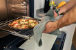 © Valentina Barreto/Stocksy - man taking pizza out of the oven